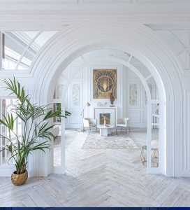 Bright and airy living space designed by Tiffany Siegel, featuring crisp white archways, herringbone wood flooring, and a statement sunburst mirror above a minimalist console table, complemented by subtle botanical accents for a fresh, inviting interior