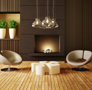 Modern and sleek living room ambiance by Tiffany Siegel, featuring a minimalist fireplace with a striking sculpture, unique pendant lights overhead, contemporary round lounge chairs, and an artistic coffee table, all set upon a warm wooden floor.